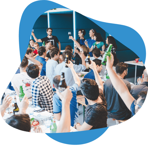 Nmbrs company culture - Together is when the magic happens. The picture shows our colleagues sitting at long dining table. Everyone is raising their glasses to congratulate the organisers of the Summer Event of 2018.
