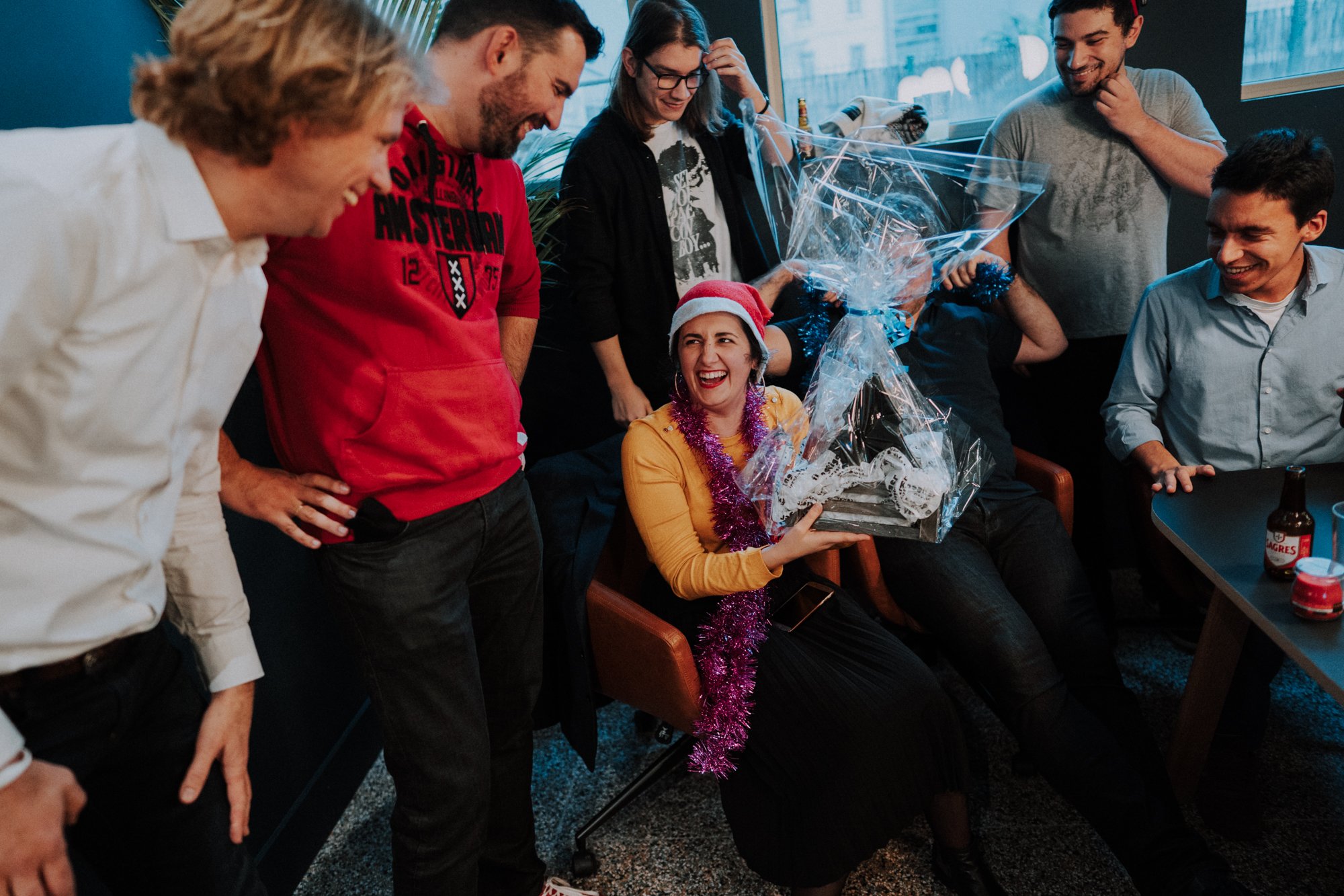 At Nmbrs, we're a tight-knit family. In the image, there is Rita, our Recruitment Lead, surrounded by her team from a game we did during the Christmas party of 2019 in Lisbon. They're laughing and celebrating having won the game.